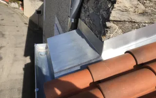 Détail d'un entablement en zinc en raccord avec un couloir de rive, la gouttière et la tuile