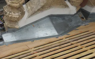 Petit chéneau à l'arrière d'une lucarne en pierre, avec création des pentes