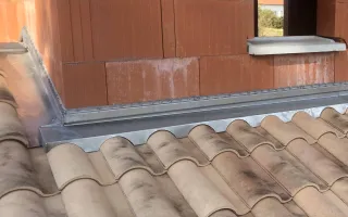 Raccord d'une bavette crantée avec un chéneau de rive et ses bandes porte-solin sur de la tuile