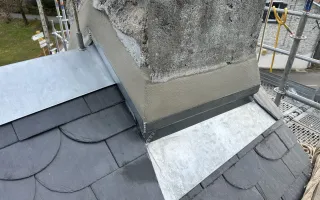 Gros plan sur l'abergement biais du clocher en zinc avec ses bandes porte solin soudées et son mortier d'étanchéité